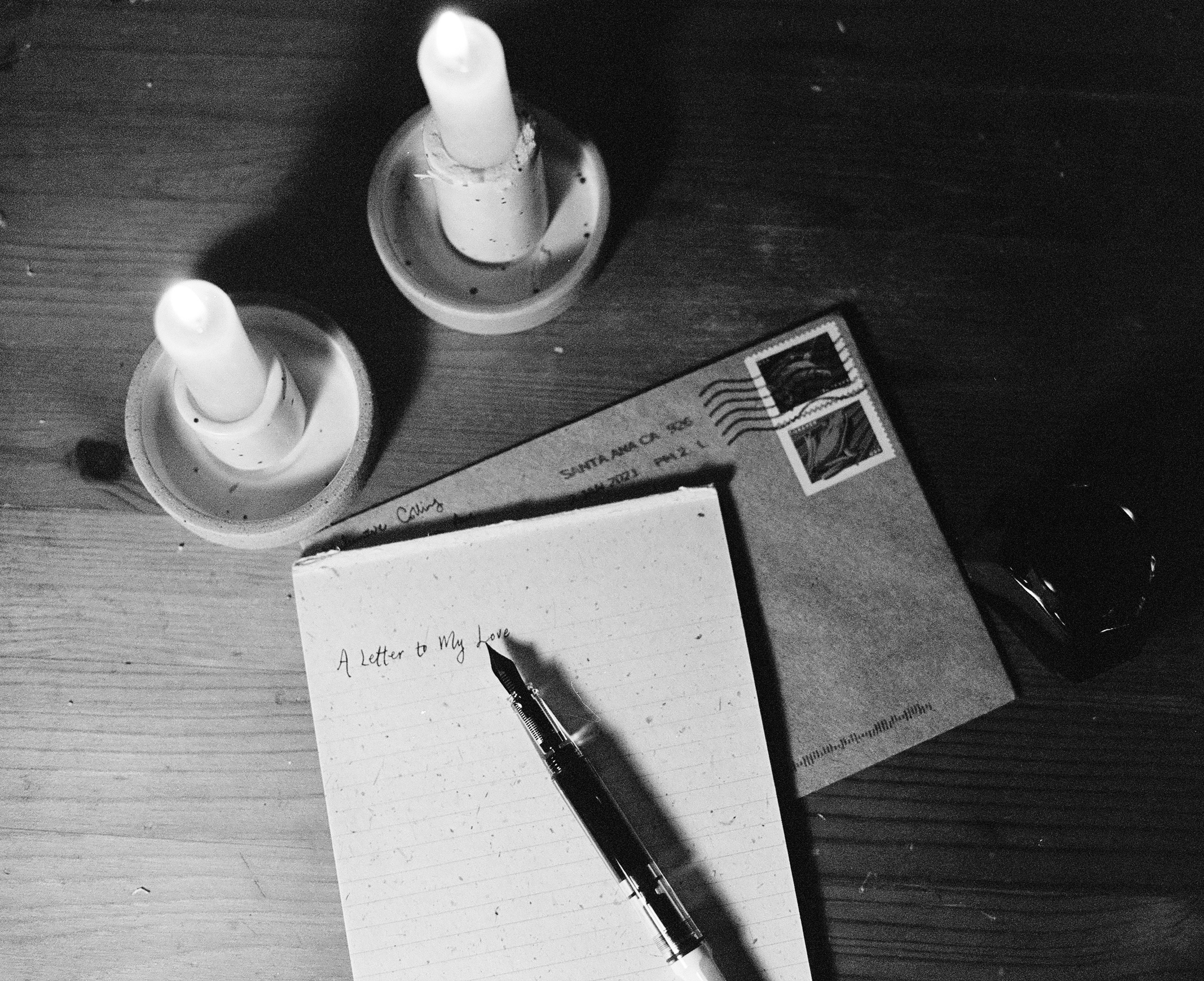 black and white photo of handwritten letter lit by two candles