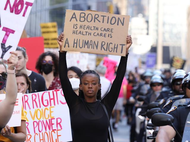 photo of black woman holding a sign reading abortion is health care/ health care is a human right. at a pro choice protest