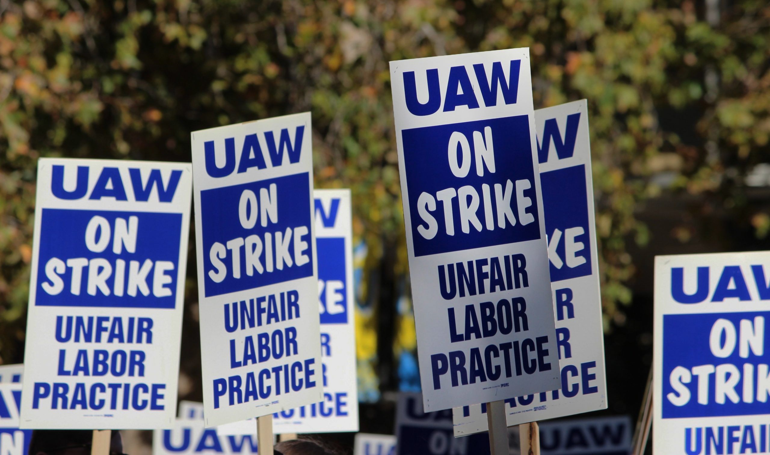 photo of UAW strike signs being raised above workers