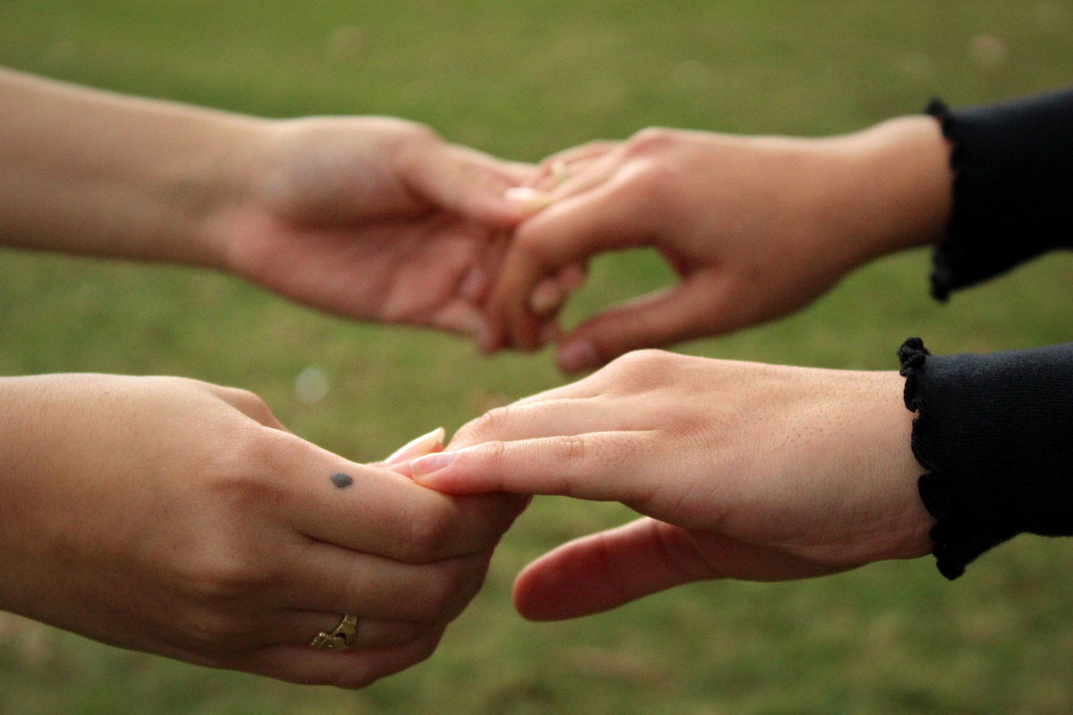 photo of two pairs of hands holding each other gently