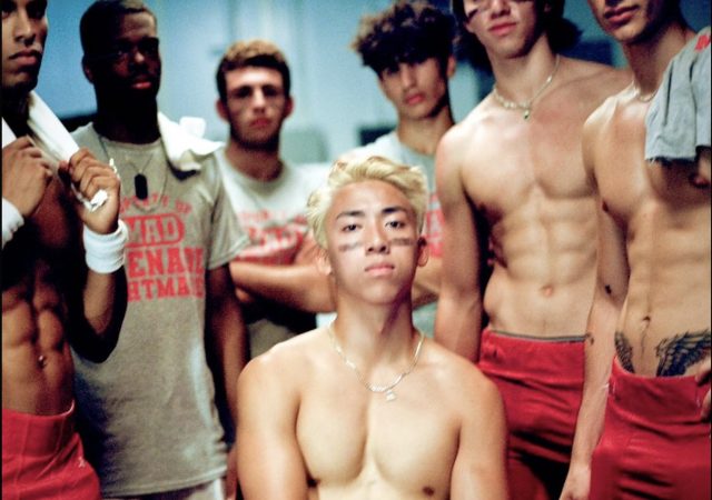 still from Mad Tsai's music video "stacy's brother" depicting him surrounded by shirtless high school jocks