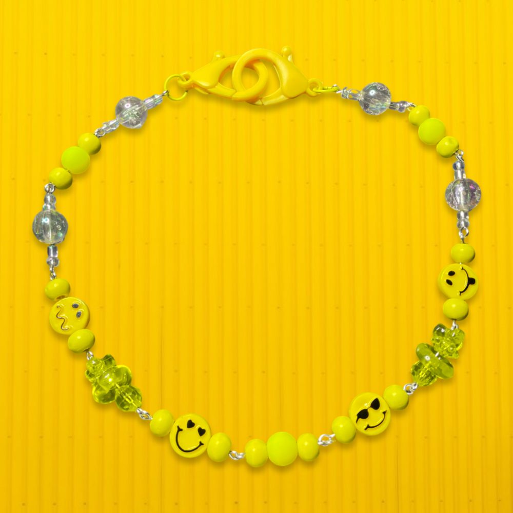 photo of a charm necklace made up of yellow beads and smiley face charms of different shapes and sizes