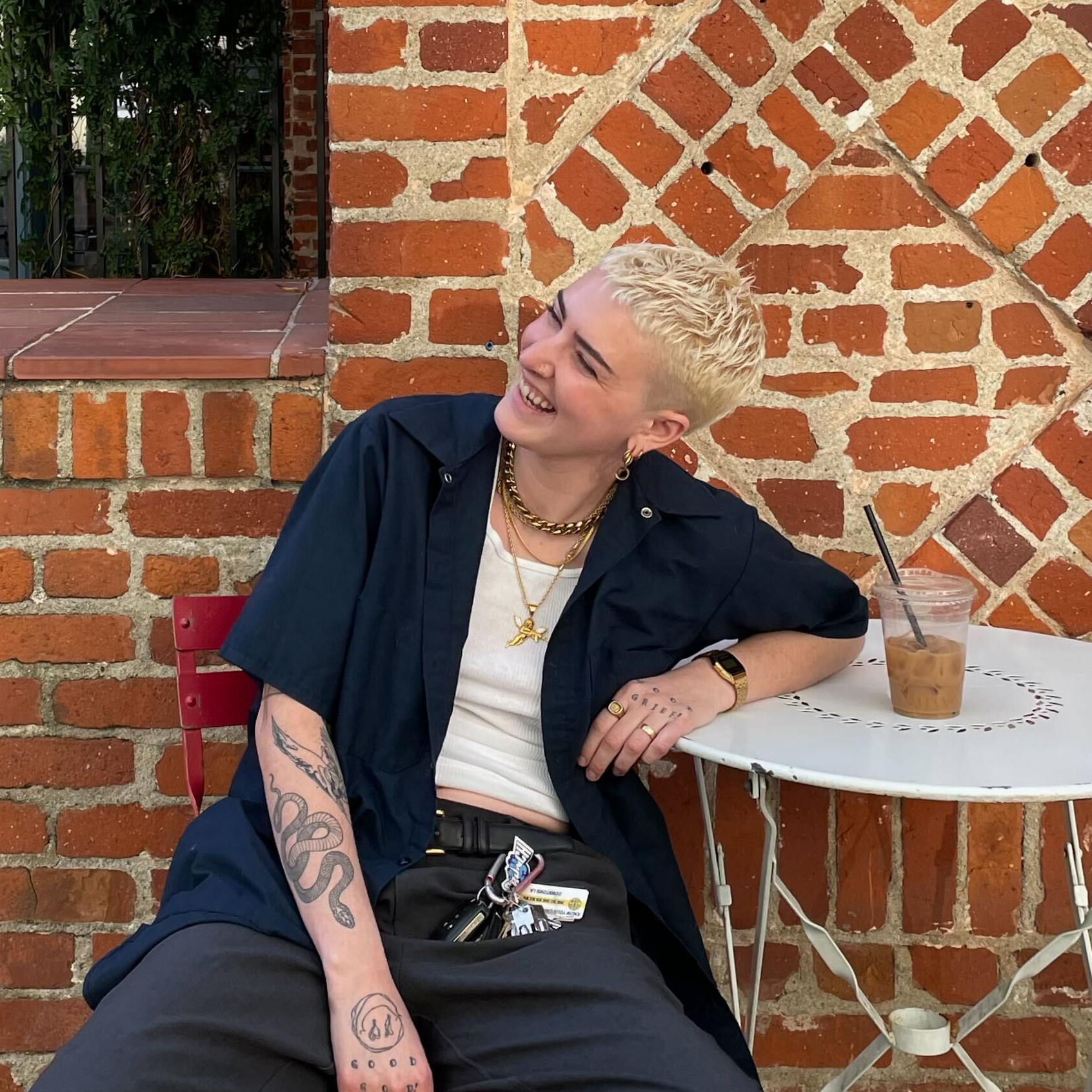 photo of Rio Romeo, a white butch nonbinary person, laughing in front of a coffee shop