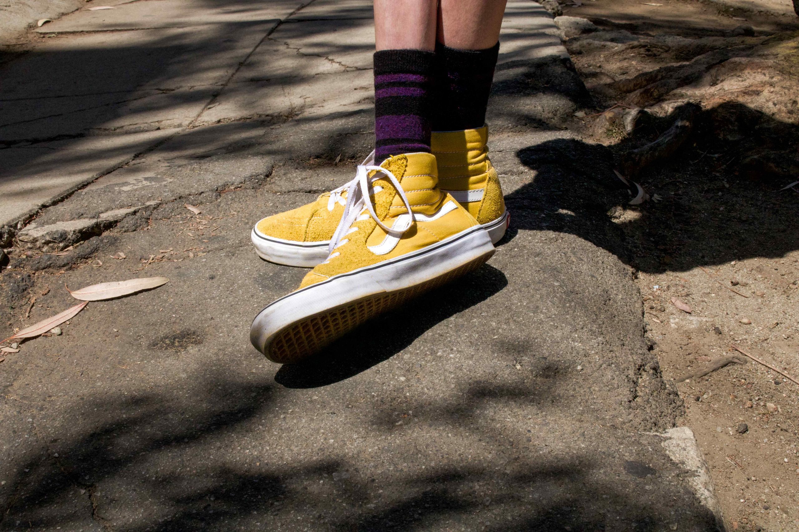 A photograph of yellow sneakers with red and black socks.