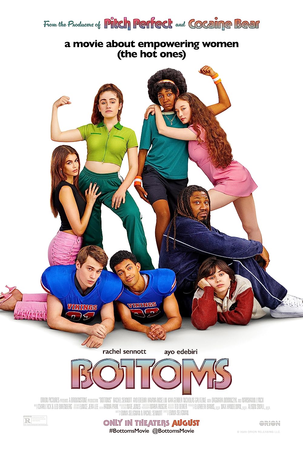 The "Bottoms" poster which includes PJ, a white girl in green making a muscle, and Josie, a black woman in teal making a muscle. Clinging to each of them is a young white woman and a young Wasian woman both wearing pink clothing items. Two football players lounge beneath them, another white woman and a Black man.