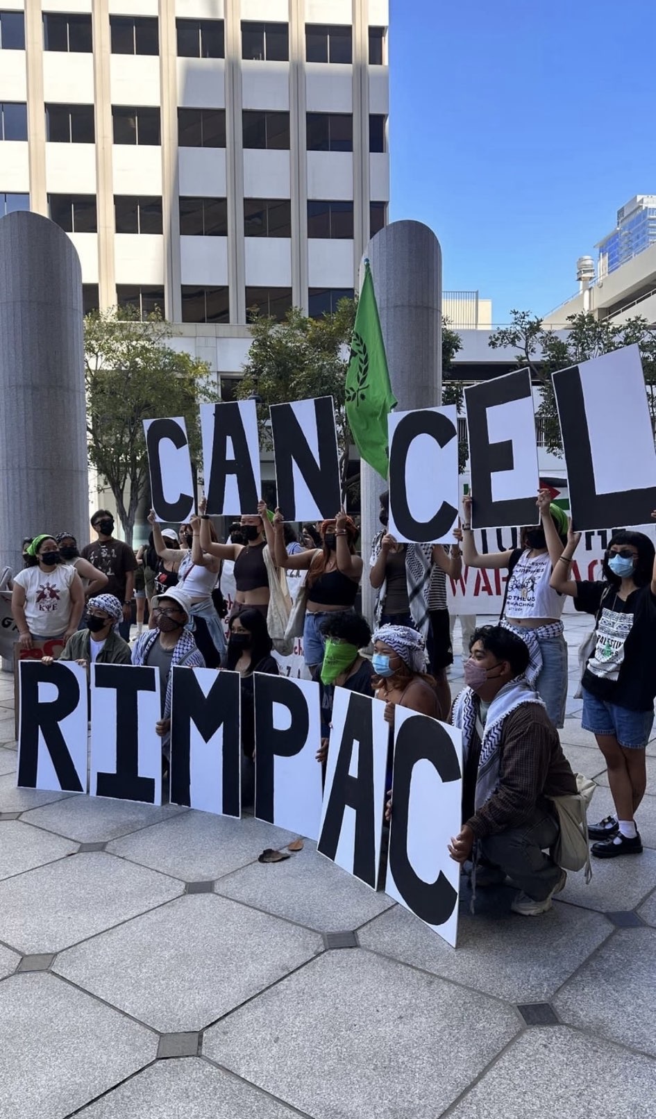 Student protestors hold up large signs which together read "Cancel RIMPAC".