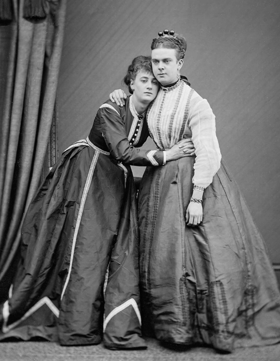 A black-and-white Victorian-era photograph of two white AMAB people dressed as women.